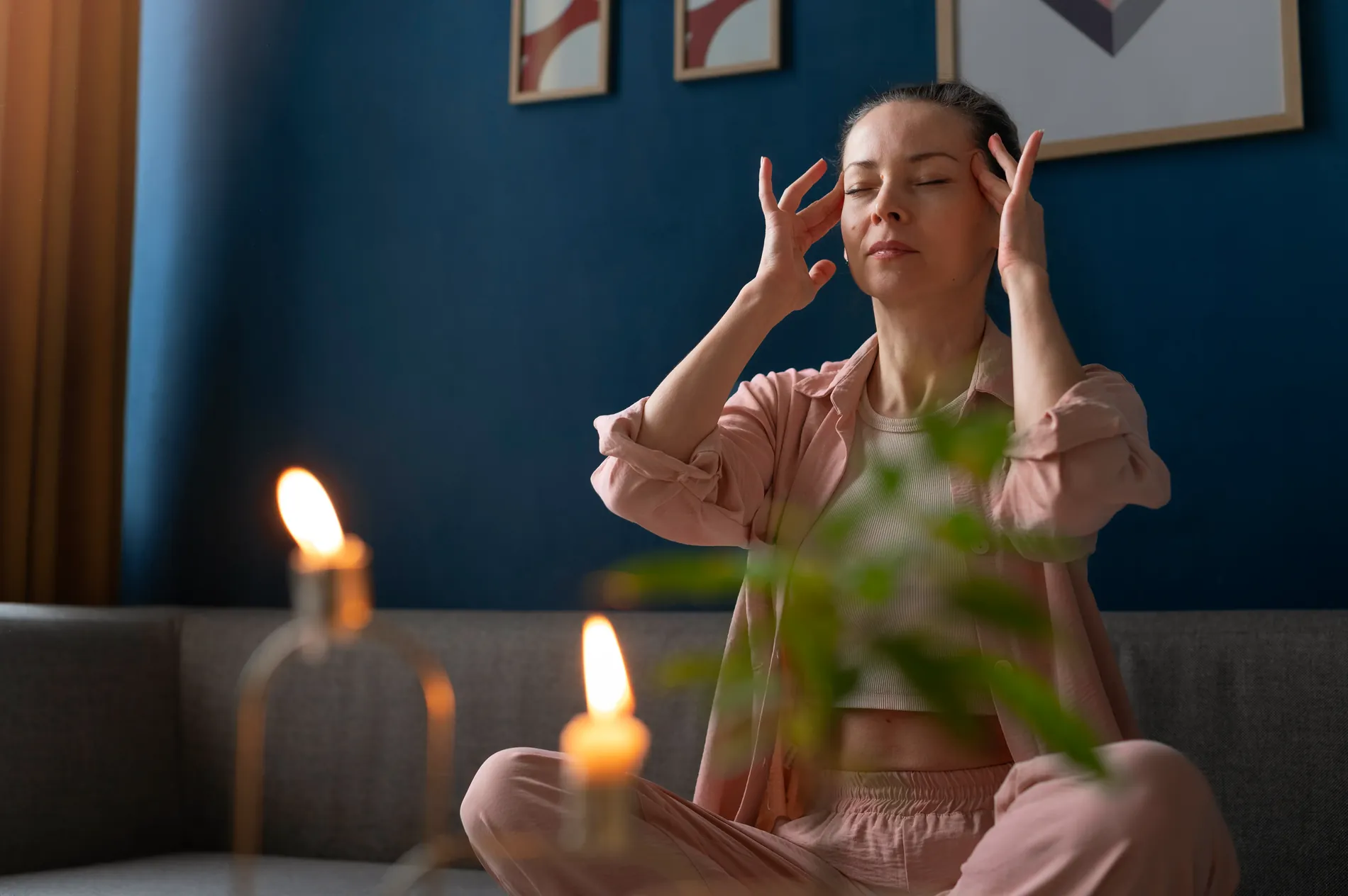 A woman sitting calmly with her eyes closed in warm candlelight, taking a quiet moment of reflection